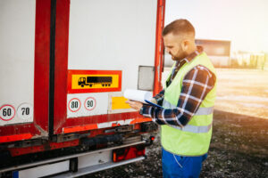 An image showing a driver conducting a pre trip inspection on a commercial vehicle before starting a journey.