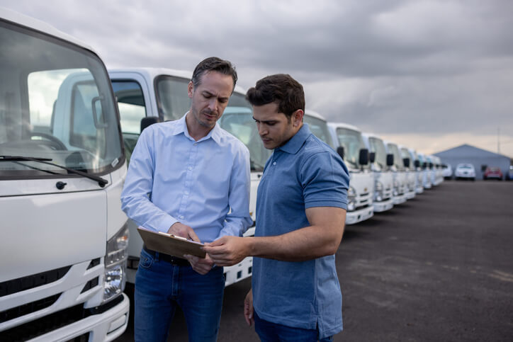 A fleet manager recruits a would be commercial driver in front of a row of parked vehicles.