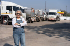 A commercial driver standing in front of oil truck after performing a pre-trip inspection on a truck