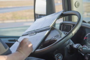 An image showing a truck driver's logbook with the words CDL Hours of Service written on it.